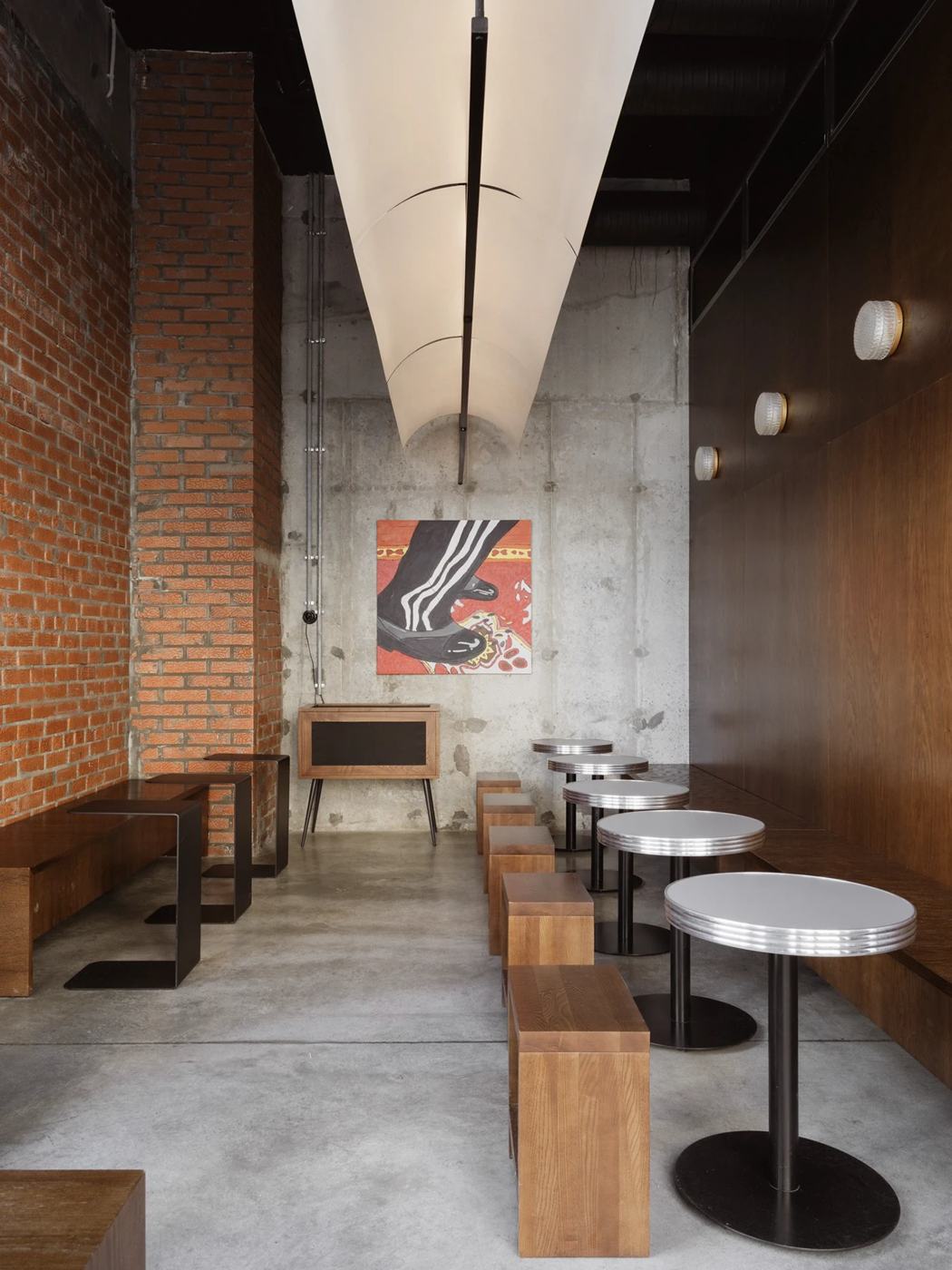Skuratov coffee roasters (Kazan) — 벽을 따라 놓은 긴 공용 벤치와 원형 테이블